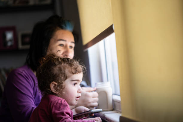 istock Mother And Daughter Looking Through Window During Covid-19 Pandemic Lockdown 1226611232