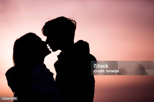 Silhouette Of Teenage Couple Kissing At Sunset Stock Photo - Download Image Now - Teenage Couple, Kissing, Teenager