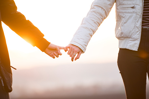 Teenage Couple Holding Hands With Little Fingers While Walking Outdoors.