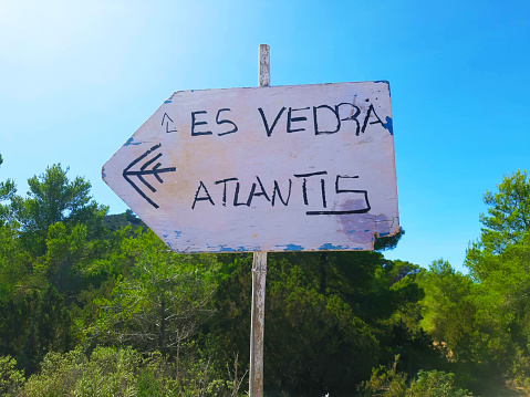 rudimentary road signs sign indicate the way to Es Vedra and to Atlantis among the green trees and the vegetation of ibiza in summer