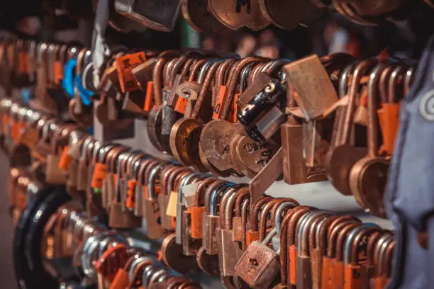 Photo of Close up shot of rusty old love locks hanging on the bridge