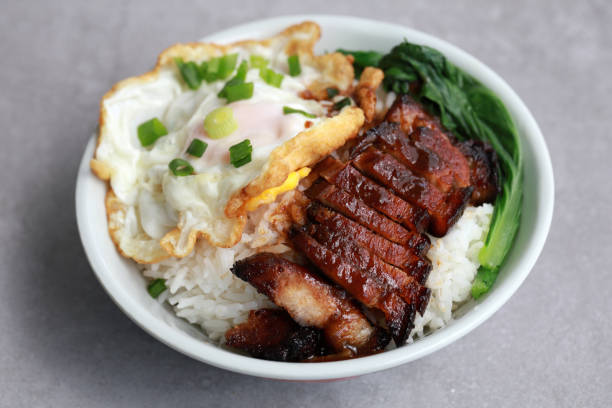 primer plano de char siu servido con arroz en un tazón con huevo frito y verduras. - cooked still life close up rice fotografías e imágenes de stock