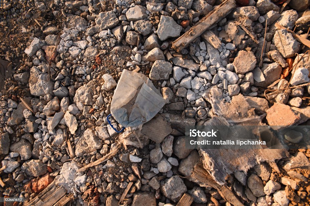 plastic rubbish ice on the stones, an old bottle thrown by lumi, stones and rubbish, environmental pollution, a piece of cloth like rubbish lies on the ground Accidents and Disasters Stock Photo