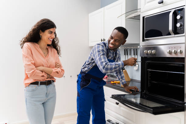 istock Woman Looking At Worker Repairing Oven 1226620445