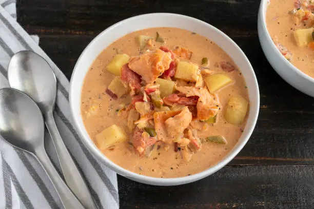 Two bowls of chowder made with seafood and vegetables