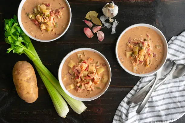 Three bowls of chowder made with seafood and vegetables