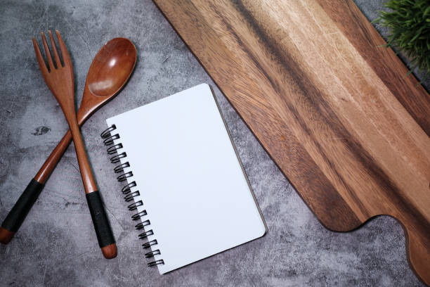 istock Notepad and chopping board with wooden fork and spoon on white table 1226623430