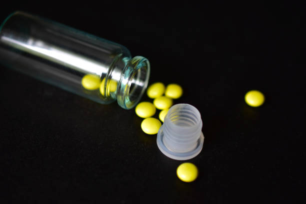 istock Glass jar and yellow tablets on a black background 1226627904