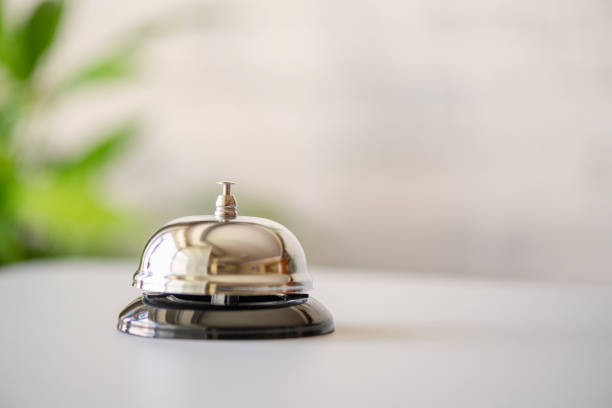 silver vintage bell on reception desk with copy space. hotel service. selective focus - sineta imagens e fotografias de stock