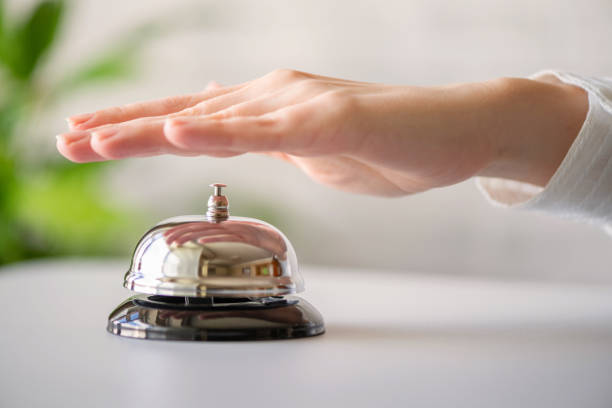 istock Hand of guest ringing in silver bell. reception desk with copy space. Hotel service. Selective focus 1226628988