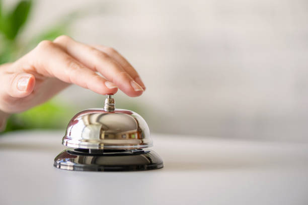 istock Hand of guest ringing in silver bell. reception desk with copy space. Hotel service. Selective focus 1226628989