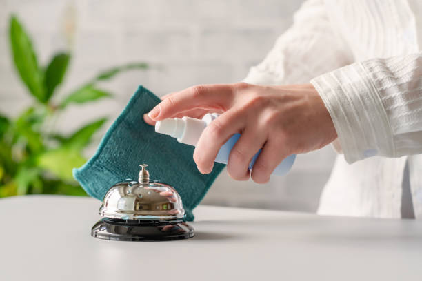 Hand of woman cleaning ringing bell on reception desk. disinfection spray, small towel. Protection from bacteria and virus. Keeping health of guests. Hotel service. Selective focus Hand of woman cleaning ringing bell on reception desk. disinfection spray, small towel. Protection from bacteria and virus. Keeping health of guests. Hotel service. Selective focus hotel occupation concierge bell service stock pictures, royalty-free photos & images