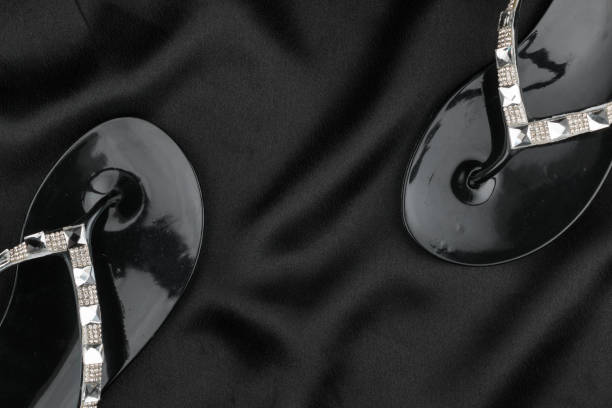 istock Beach flip flops decorated with rhinestones stand on black fabric. Top view. 1226639080