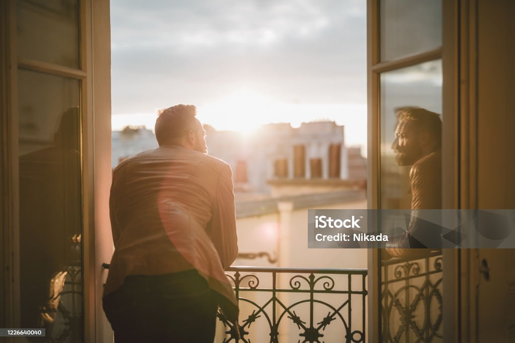 Bearded man looking out over the city at sunrise Men Stock Photo