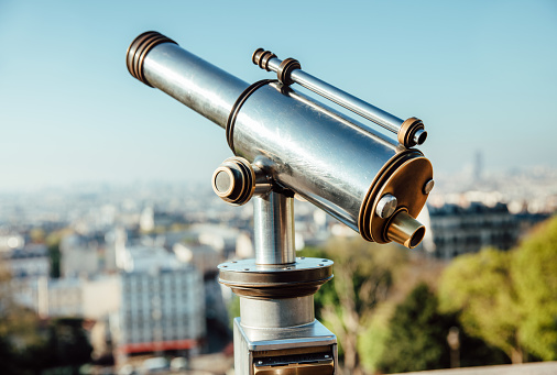 Old coin telescope looking over paris cityscape \nParis, France