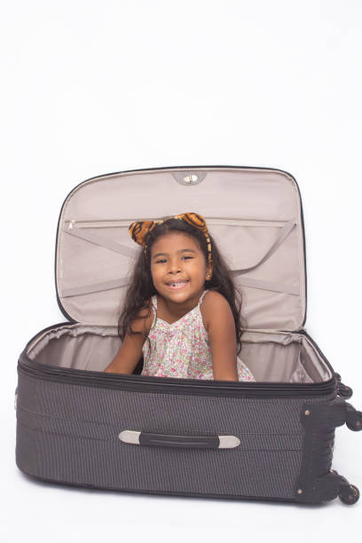 Beautiful girl playing inside a suitcase, isolated on white.
