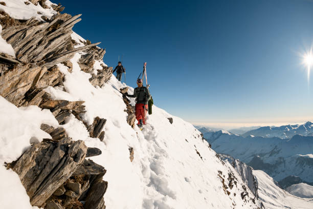 istock men with ski equipment go down from mountain by snow trail 1226641283