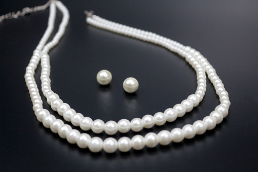 White pearl jewelry pendant and earrings on black background