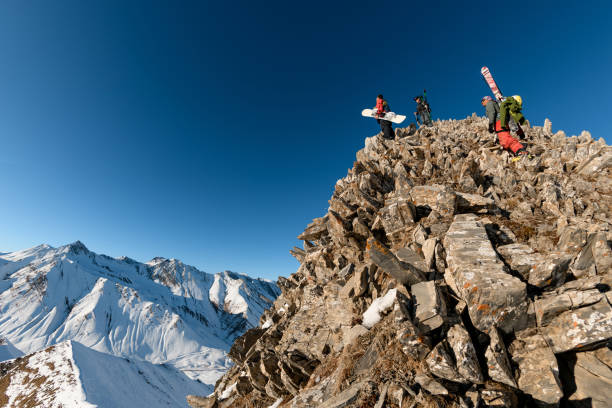 istock Three men with skis and snowboard on top of stone mountain. 1226643270