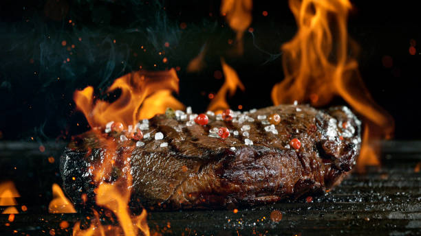 istock Tasty beef steak on cast iron grate with fire flames. 1226644575