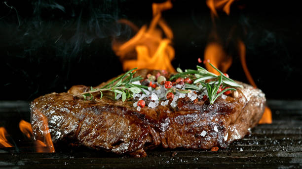 istock Tasty beef steak on cast iron grate with fire flames. 1226644590