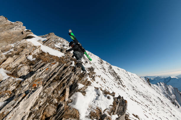 istock Man with ski equipment on his back climbs on rocky mountain 1226645038