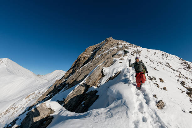 istock one man with ski equipment rises on snowy mountain. 1226646240