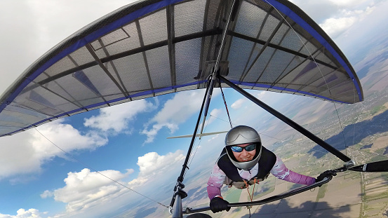Feliz mujer sonriente ahorca piloto en el cielo con nubes cúmulos. Selfie por cámara de acción photo