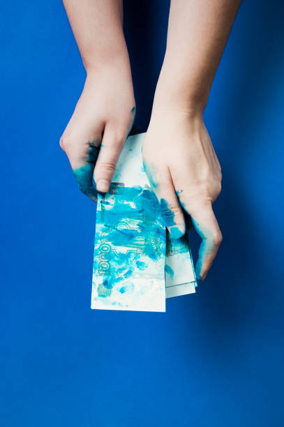 istock Concept : two hands hold few Russian banknotes - 1000 rubles - covered by blue paint on a blue background 1226650814