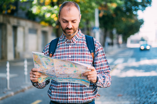 Shot of a young man looking at a map while touring a foreign city.