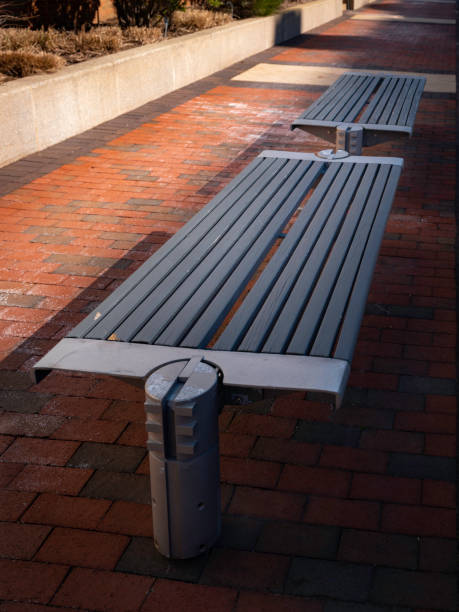 Modern flat gray park benches on the harbor walkway Empty chairs on the red brick footpath along the harbor in East Boston, Massachusetts east boston stock pictures, royalty-free photos & images