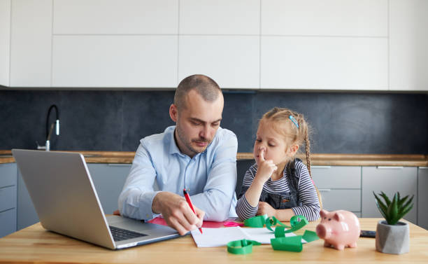 istock Father Working from home on laptop during quarantine. Young father does homework with his little daughter 1226655868