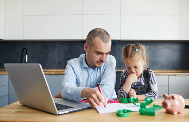 istock Father Working from home on laptop during quarantine. Young father does homework with his little daughter 1226655888