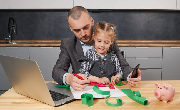 istock Father Working from home on laptop during quarantine. Young father does homework with his little daughter 1226655909