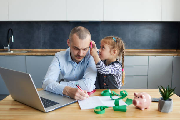 istock Father Working from home on laptop during quarantine. Young father does homework with his little daughter 1226656007