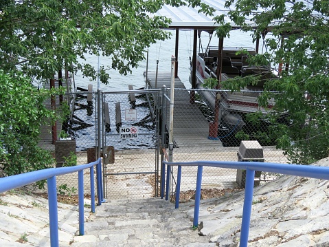 Boat docked at marina behind locked gate. View from land. Restrictive Signs.