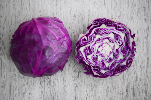 A raw red cabbage cut in two, on a table.