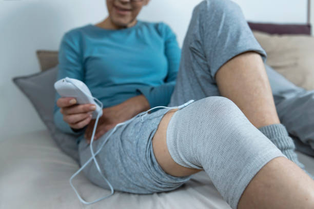 estimulación nerviosa eléctrica transcutánea, mujer mayor que hace terapia física de rodilla con tómo de electrodo tens conductivo - rheumatic fotografías e imágenes de stock