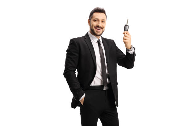 Happy man in a black suit holding a car key Happy man in a black suit holding a car key isolated on white background car key photos stock pictures, royalty-free photos & images