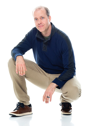 Front view of aged 30-39 years old mid adult crouching in front of white background who is happy