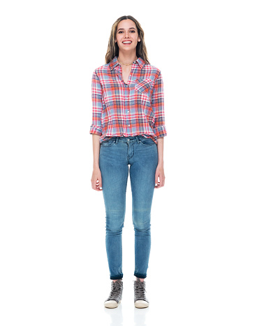 Full length of aged 20-29 years old who is beautiful caucasian young women standing in front of white background wearing jeans who is cheerful with hand by side