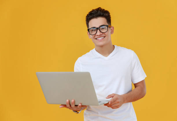istock Cheerful ethnic man with laptop on bright backdrop 1226663876