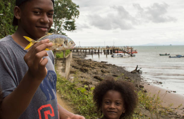 Bahía Solano, Chocó, Colombia. June 26, 2016: Teenage boy shows a fish in his hand and a girl next to him pose near the beaches of the pacific sea of ​​Bahia Solano.