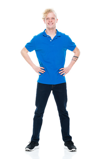 Front view of aged 20-29 years old with blond hair caucasian male standing in front of white background wearing jeans who is successful with hand on hip