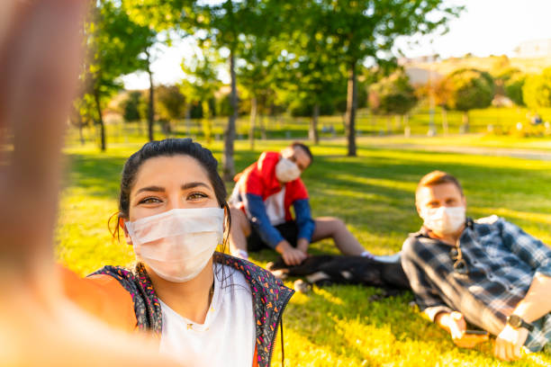 istock Cheerful university student taking selfie with friends sitting on grass 1226665494