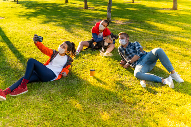 istock Cheerful university student taking selfie with friends sitting on grass 1226665548