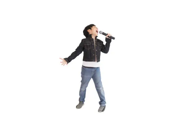 Photo of A portrait of a cute Asian elementary school boy wearing a pair of jeans and a black jacket enjoying singing.