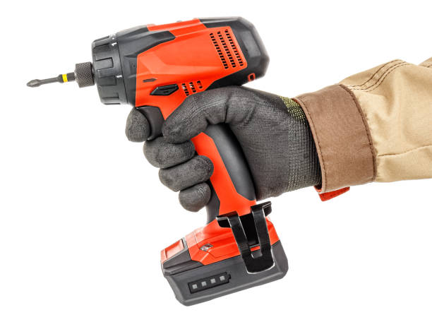 istock Modern red cordless screwdriver in worker hand in black protective glove and brown uniform isolated on white background 1226670947