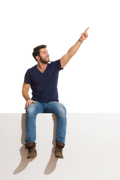 istock Handsome Man Is Sitting On A Top Looking Away, Pointing Up And Smiling. 1226674001