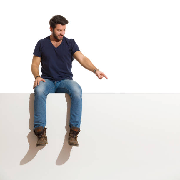 istock Happy Handsome Man Is Sitting On A Top Looking Away And Pointing Down. 1226674003